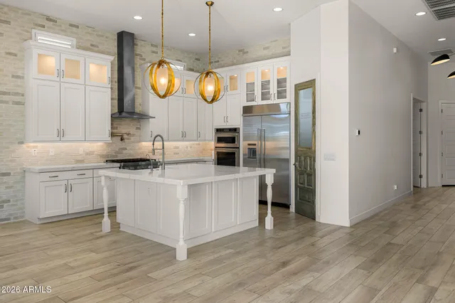 a kitchen with stainless steel appliances granite countertop a stove a refrigerator a kitchen island a dining table and chairs with wooden floor
