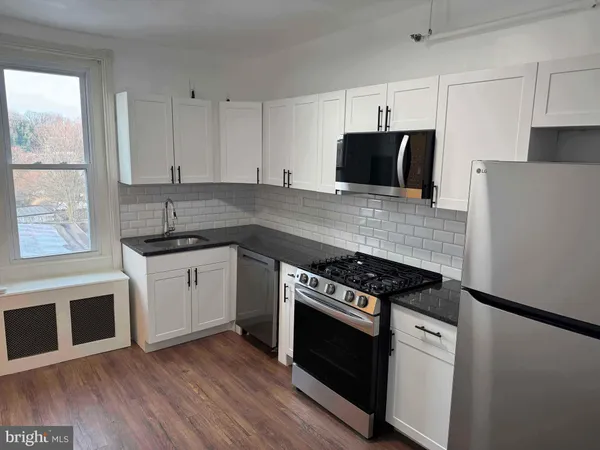 a kitchen with cabinets appliances and a wooden floor