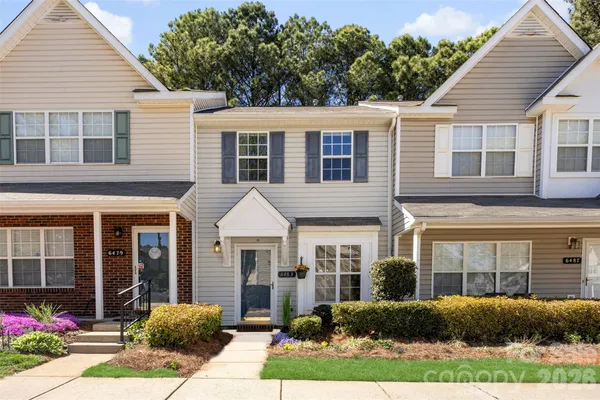 a view of a brick house with large windows and potted plants