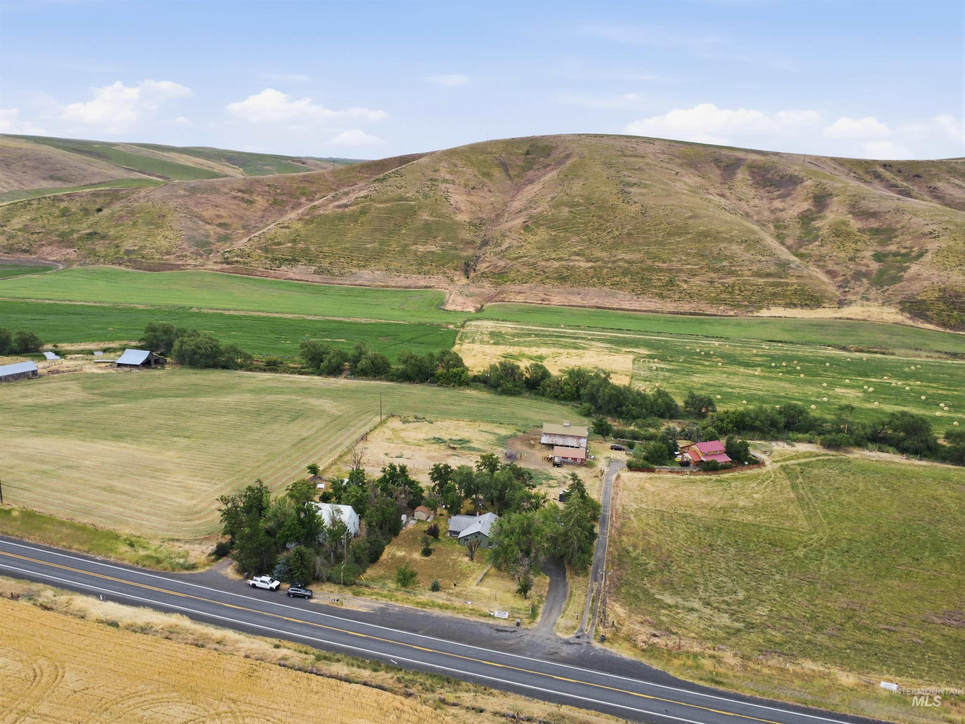 259 Highway 12 Pomeroy, WA 99347 - Photo 3 of 45 Expansive agricultural land featuring a paved road, multiple structures, and distant hills