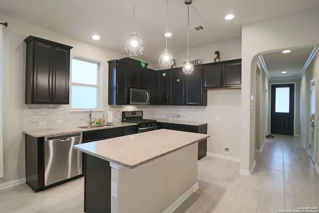 a kitchen with kitchen island granite countertop a stove and a sink
