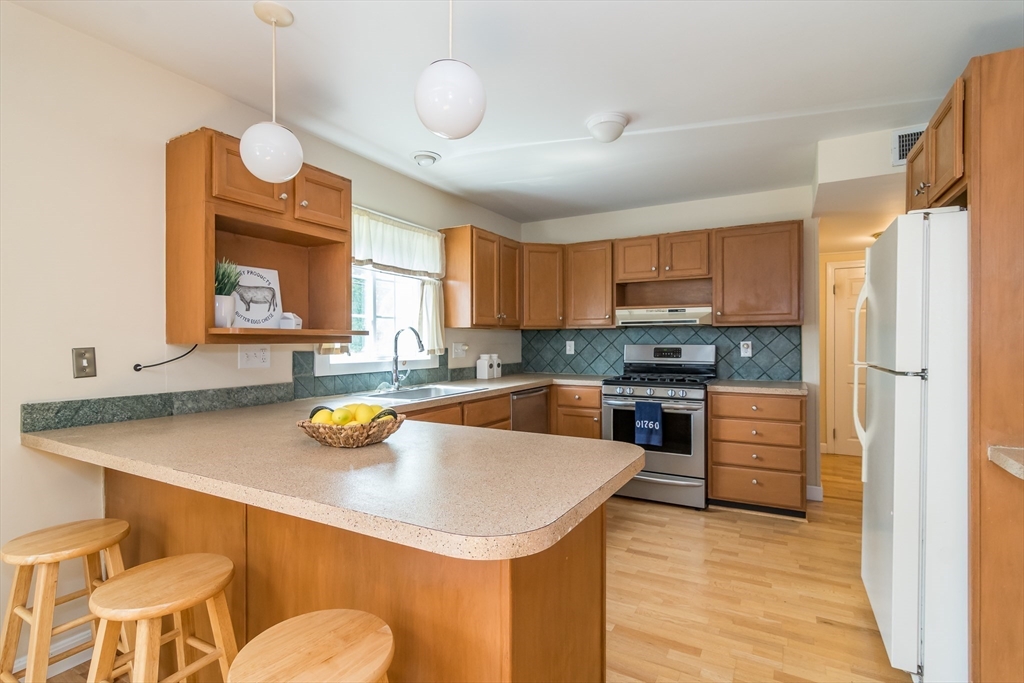 79 Mill Street Natick, MA 01760 - Photo 3 of 21 a kitchen with a refrigerator a stove a sink and a dining table with wooden floor