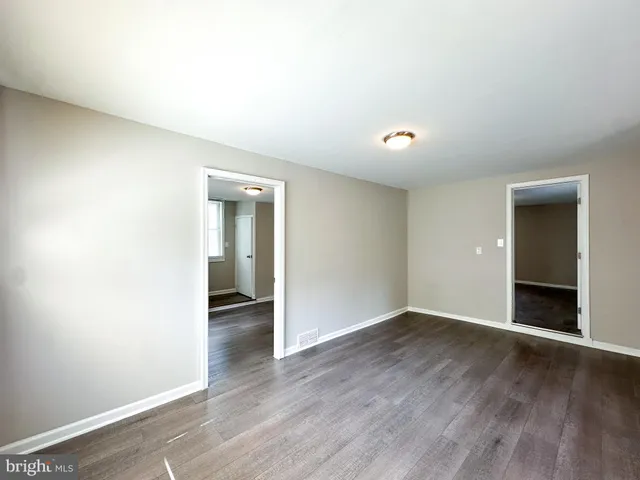 an empty room with wooden floor and bathroom