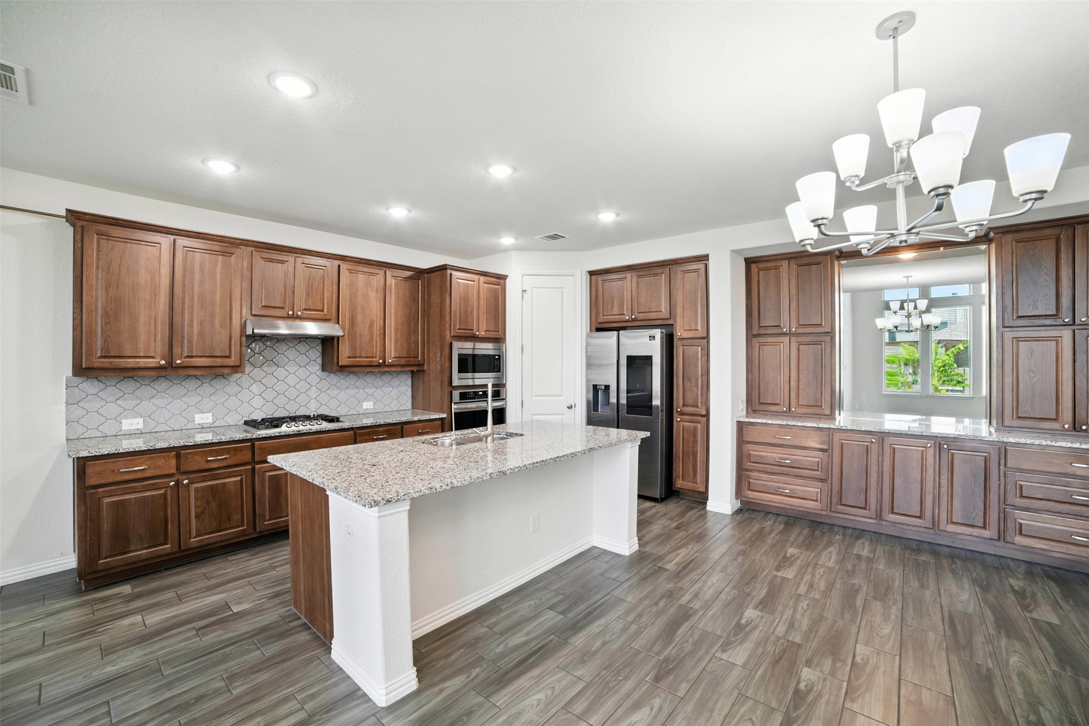 3054 Columbus Loop Round Rock, TX 78665 - Photo 7 of 40 Kitchen with appliances with stainless steel finishes, dark wood finished floors, a chandelier, tasteful backsplash, and an island with sink
