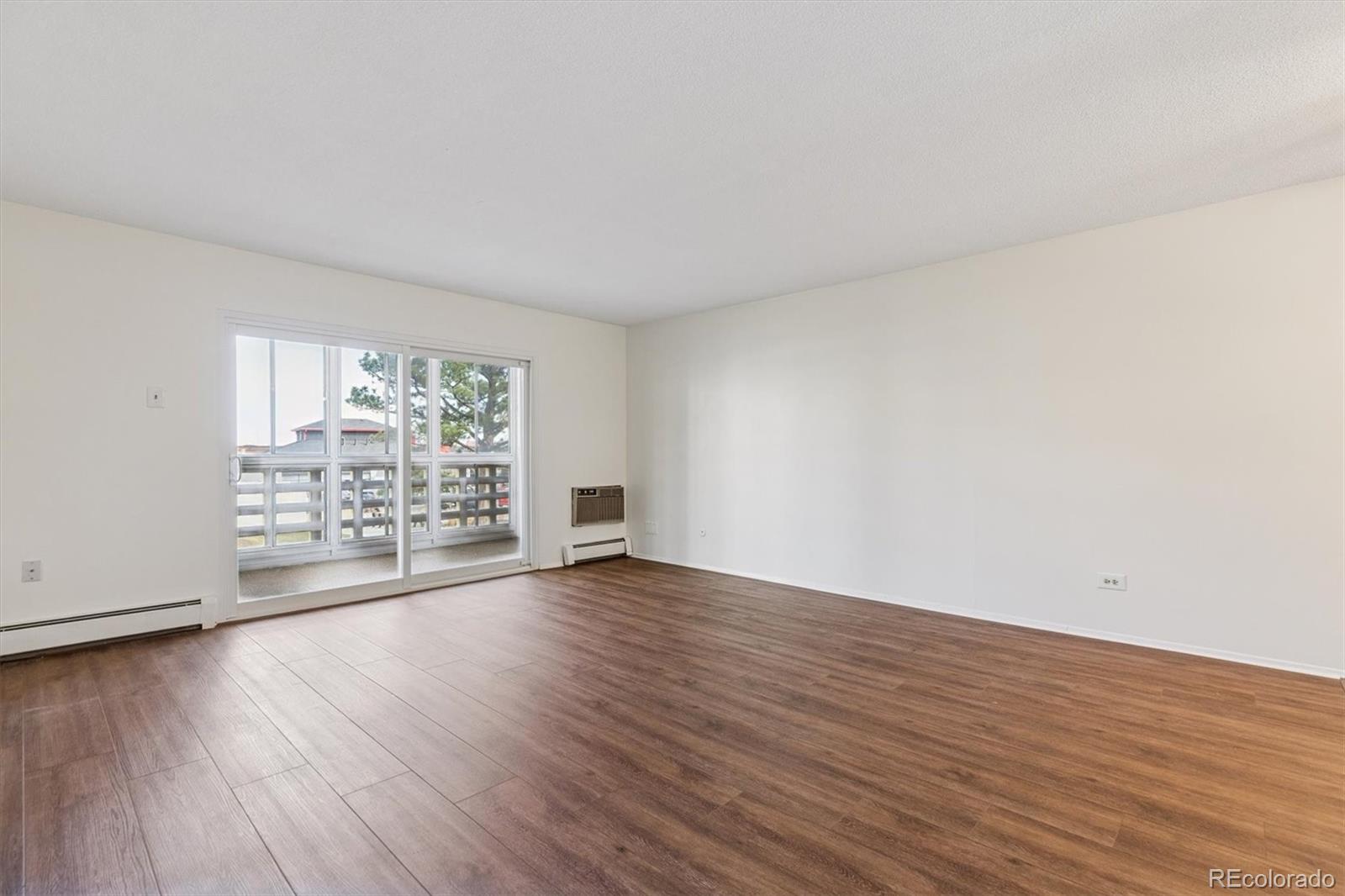 350 South Clinton Street, Unit 8B Denver, CO 80247 - Photo 6 of 50 a view of an empty room with wooden floor and a window