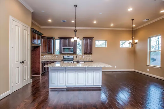 a kitchen with kitchen island granite countertop a sink stove and cabinets