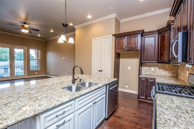 a kitchen with stainless steel appliances granite countertop a stove a sink and a microwave