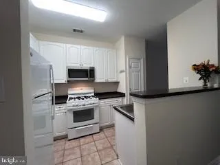 a kitchen with granite countertop white cabinets and stainless steel appliances