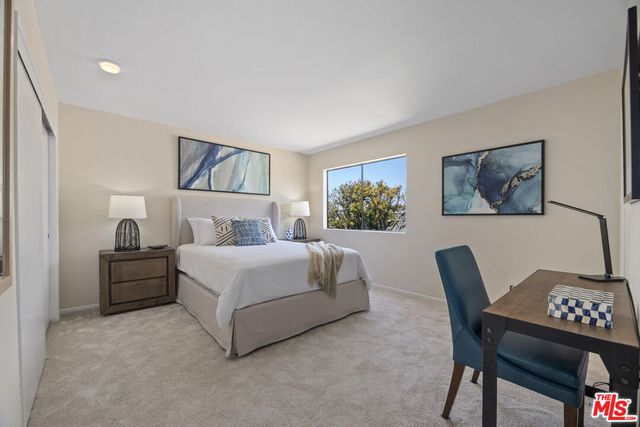 a bedroom with a bed paintings on wall and a window