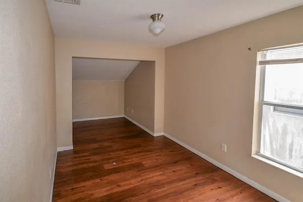 a view of an empty room with wooden floor and a window