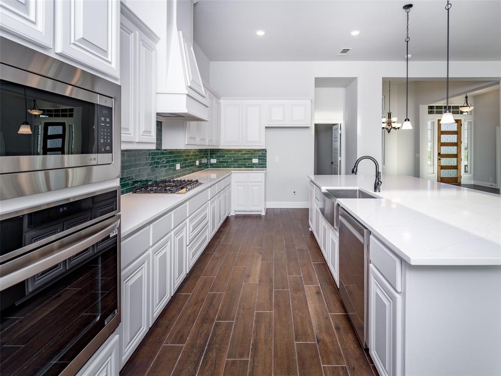 2108 Charters Circle Nevada, TX 75173 - Photo 9 of 37 Kitchen with decorative light fixtures, stainless steel appliances, white cabinetry, wood tiled floors, and a spacious island