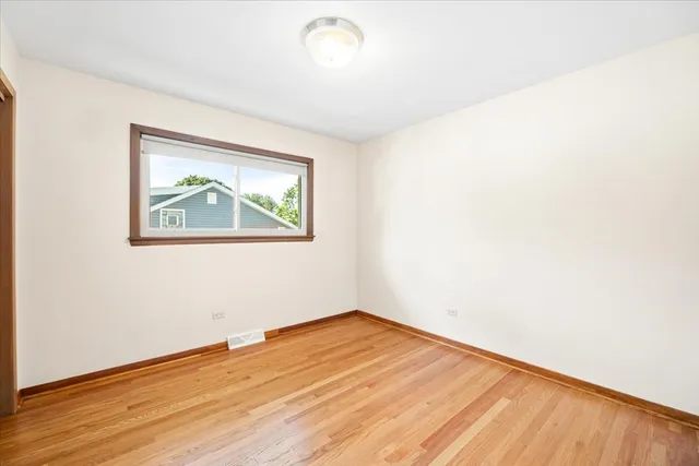 an empty room with wooden floor and window