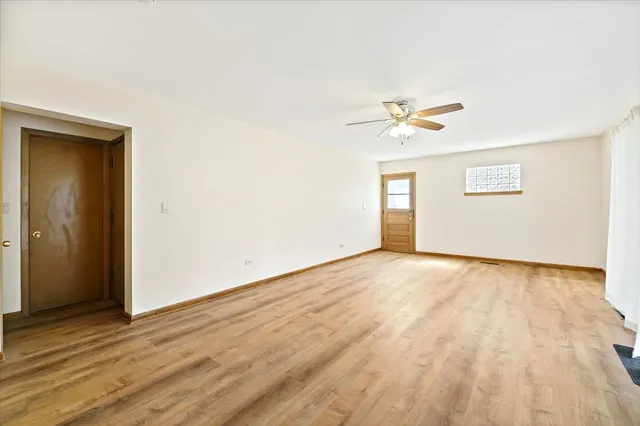 an empty room with wooden floor and ceiling fan