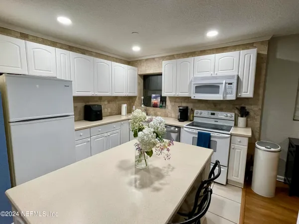 a kitchen with stainless steel appliances a white refrigerator a stove a sink a microwave a dining table and chairs