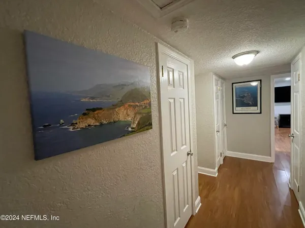 a view of a hallway to room with wooden floor and windows