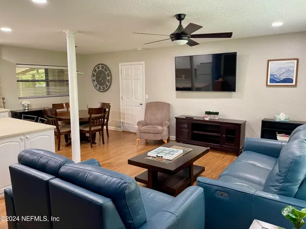 a living room with furniture kitchen view and a window