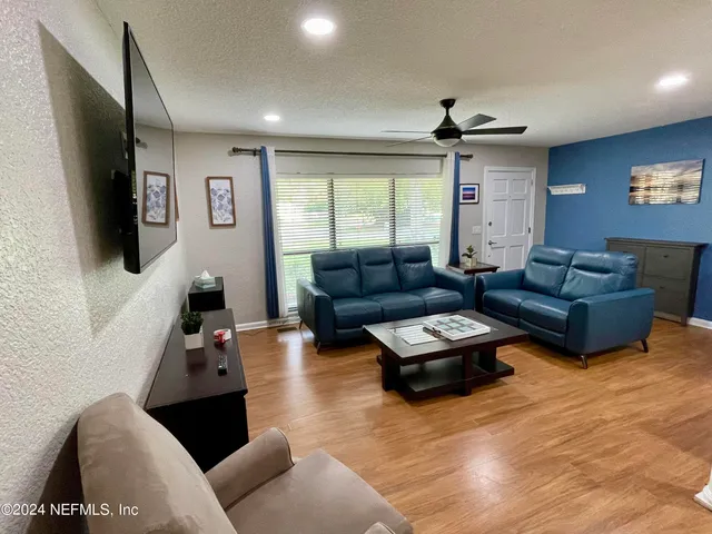 a living room with furniture flat screen tv and a large window
