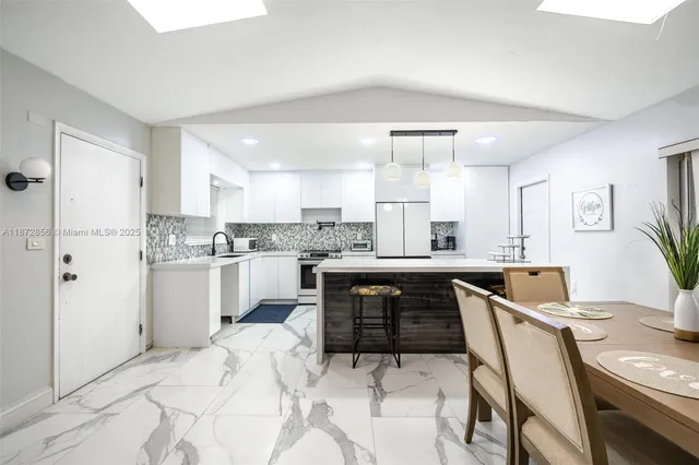 a kitchen with white cabinets and refrigerator
