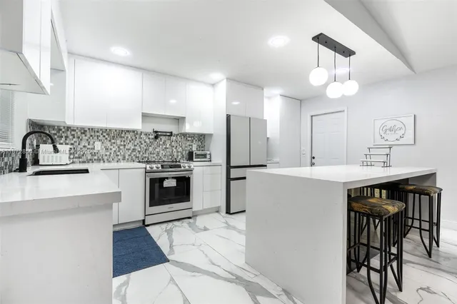 a kitchen with kitchen island a sink stainless steel appliances and cabinets