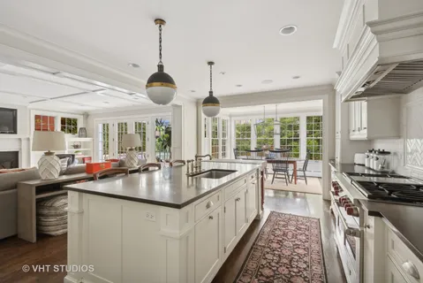 a kitchen with kitchen island granite countertop a table chairs stove and white cabinets