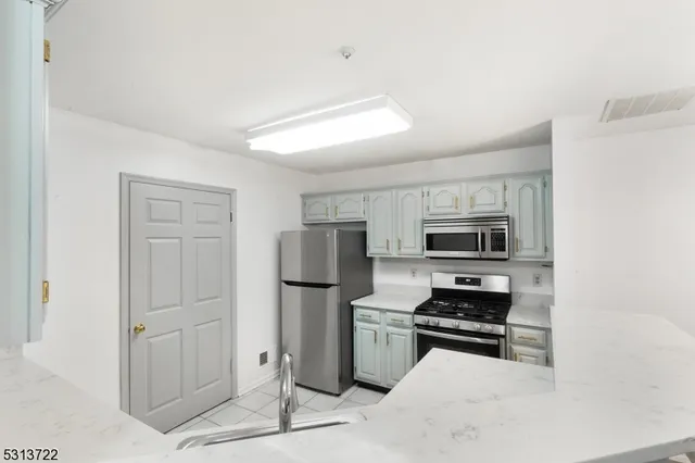 a kitchen with stainless steel appliances a refrigerator a stove top oven and white cabinets