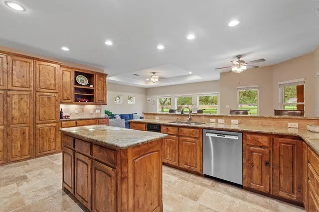 a kitchen with stainless steel appliances granite countertop a refrigerator a stove a sink a dining table and chairs with wooden floor