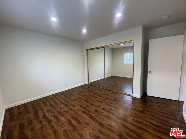 an empty room with wooden floor & windows