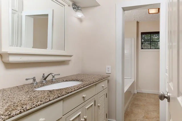 a bathroom with a granite countertop sink and a mirror