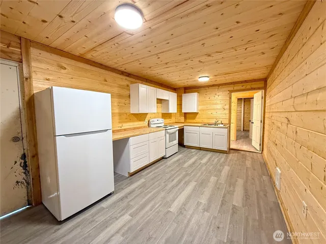 a kitchen with a refrigerator a sink and dishwasher with wooden floor
