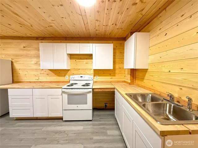 a kitchen with stainless steel appliances granite countertop a sink a stove and a wooden floors