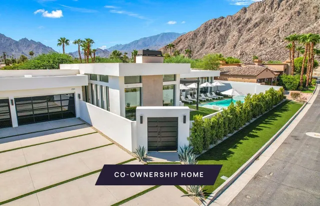 a view of a street with a couple of cars parked in front of house