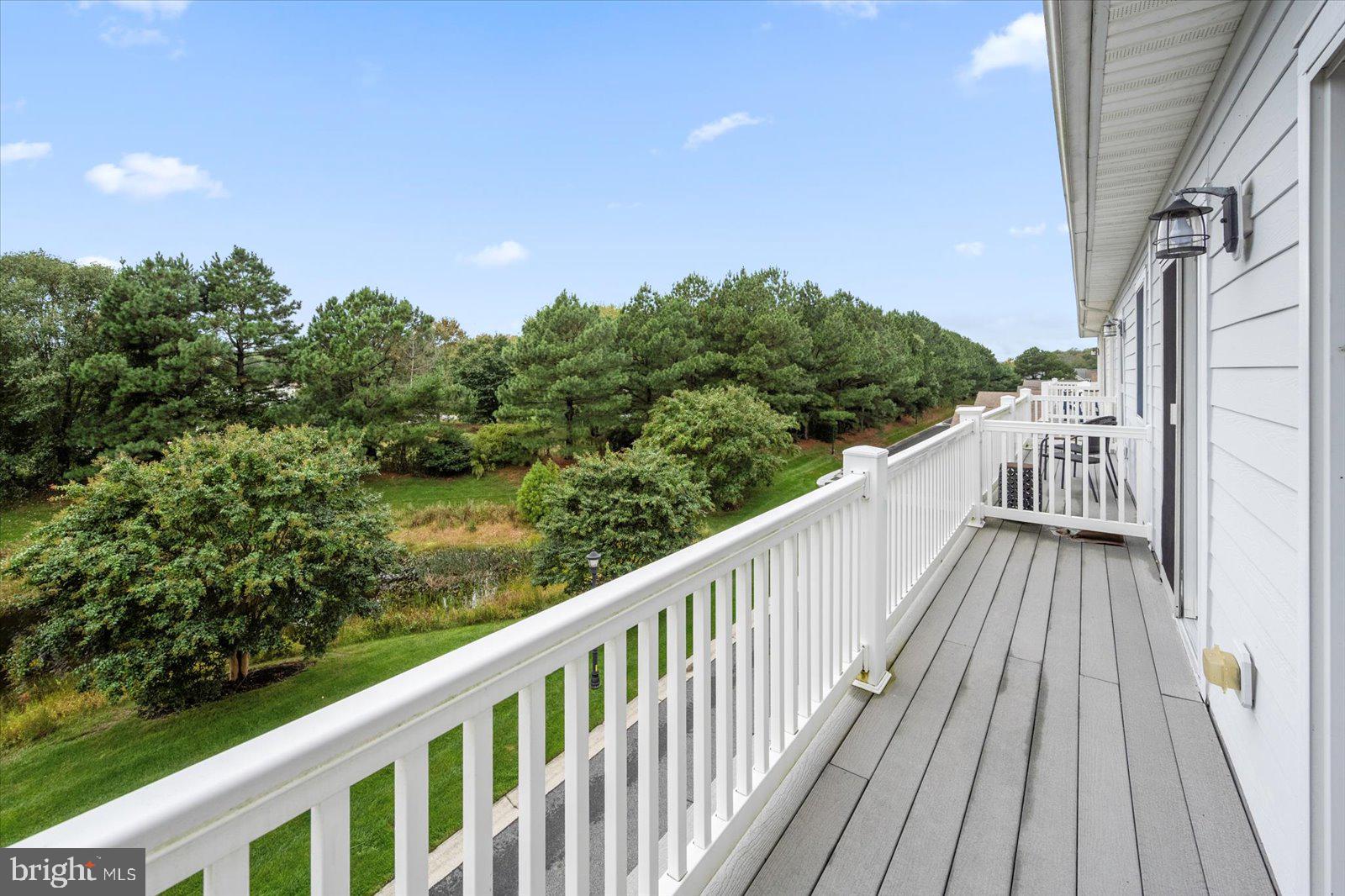 11446 West Sand Cove Road Selbyville, DE 19975 - Photo 48 of 104 a balcony with wooden floor and trees in the background