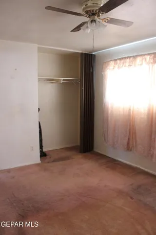 an empty room with windows and fan