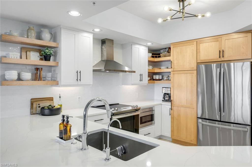 325 Dunes Boulevard, Unit 604 Naples, FL 34110 - Photo 12 of 41 a kitchen with stainless steel appliances a refrigerator and a stove top oven
