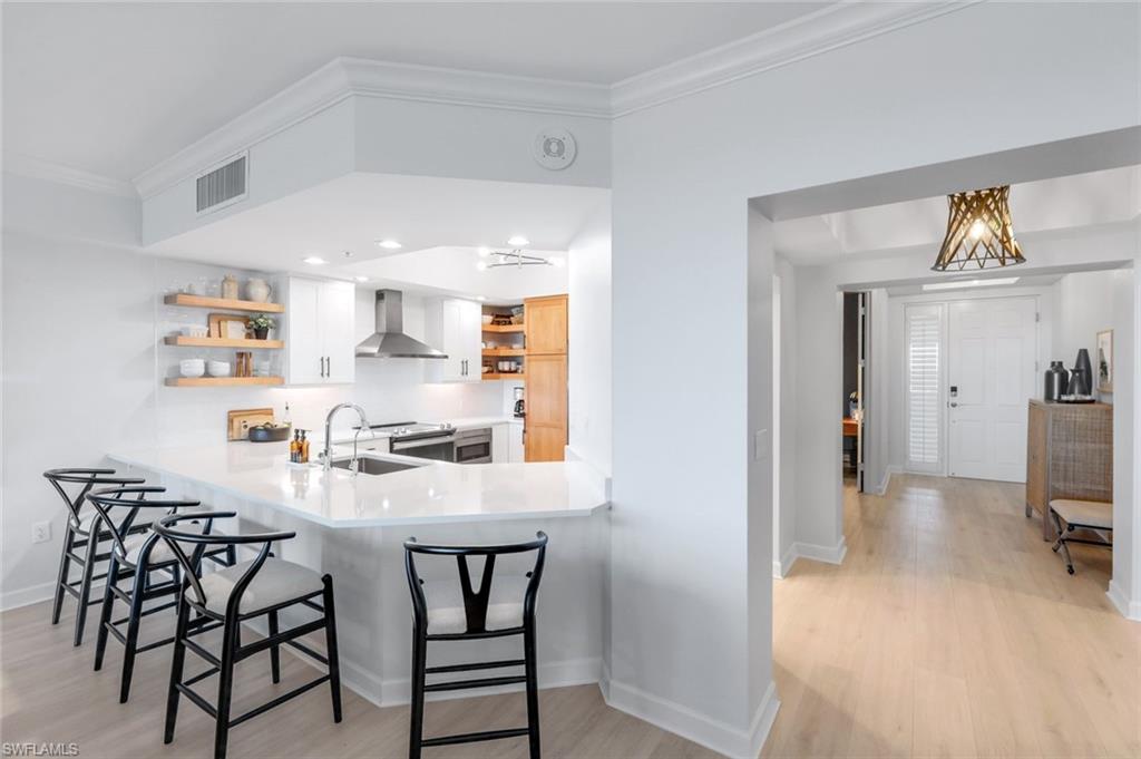 325 Dunes Boulevard, Unit 604 Naples, FL 34110 - Photo 8 of 41 a kitchen with stainless steel appliances a dining table chairs and a refrigerator