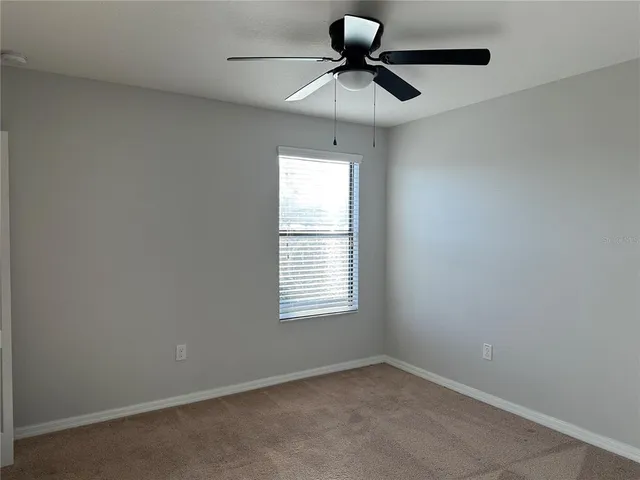 an empty room with window and ceiling fan