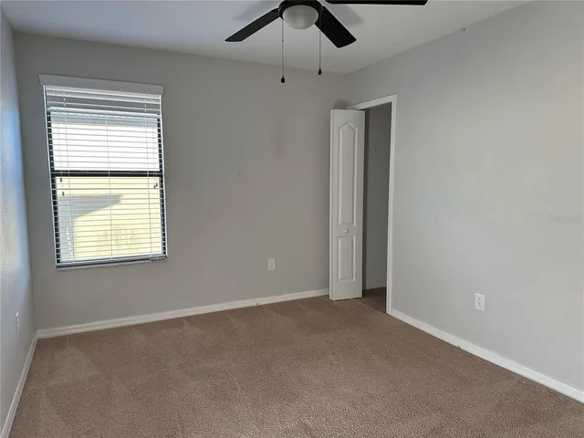 an empty room with a window and a fan