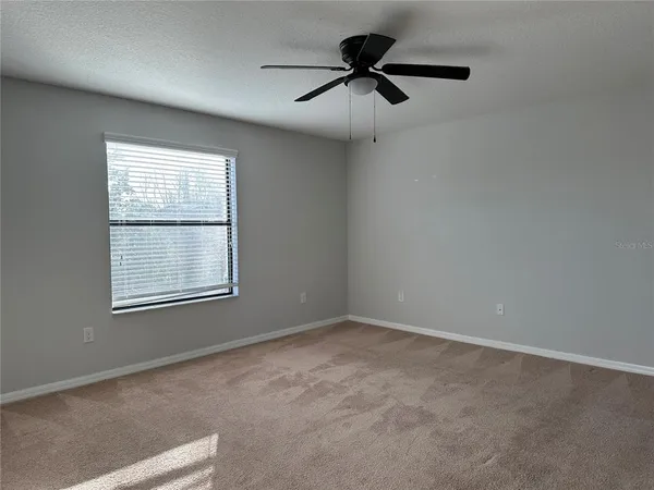 an empty room with a window and a fan