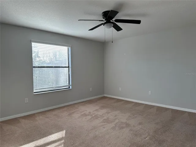 an empty room with a window and a fan