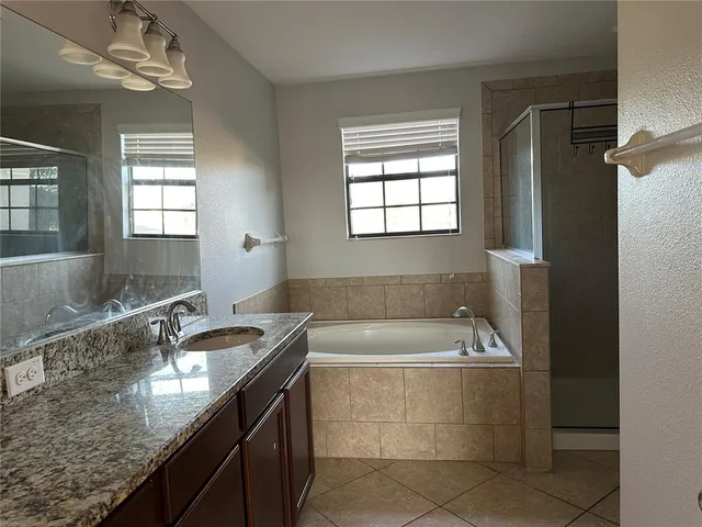a bathroom with a granite countertop bathtub sink and mirror