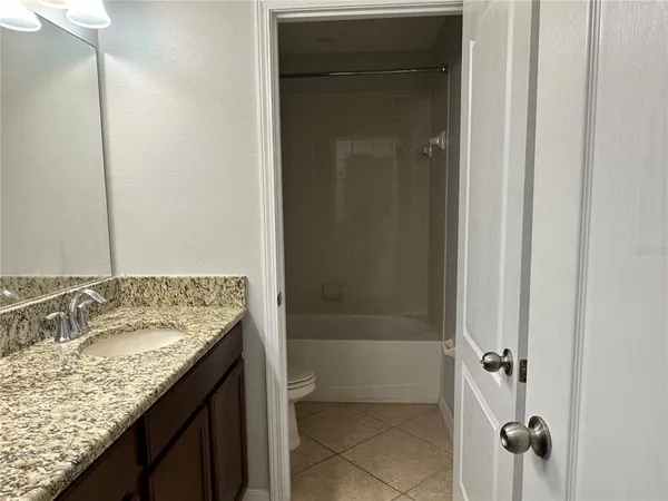 a bathroom with a granite countertop sink a mirror and shower