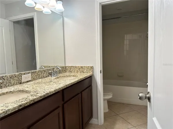a bathroom with a granite countertop sink a toilet and shower