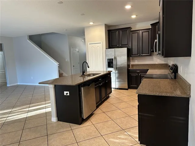 a kitchen with stainless steel appliances granite countertop a refrigerator a sink and a stove