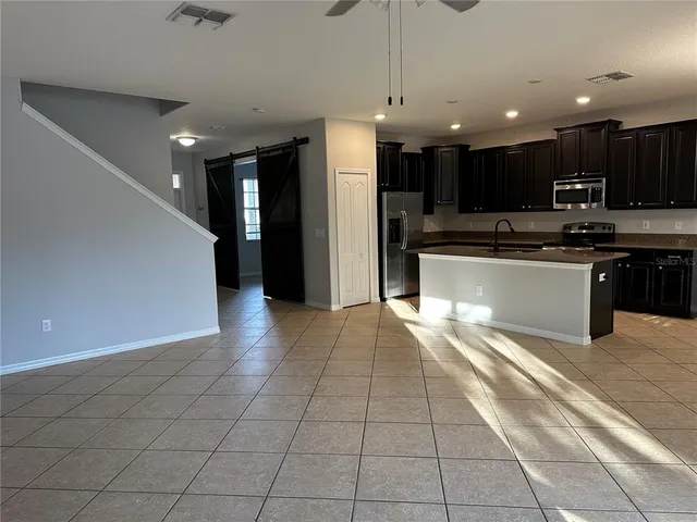 a large kitchen with stainless steel appliances kitchen island granite countertop a refrigerator a stove top oven and a sink with granite countertops