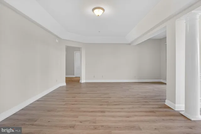 an empty room with wooden floor chandelier fan and windows