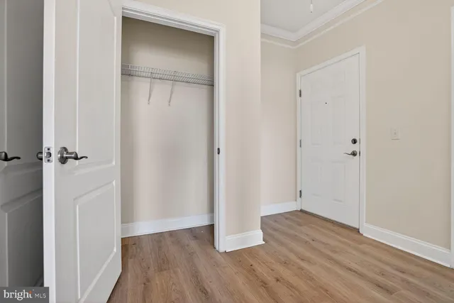 a view of an empty room with a window and wooden floor