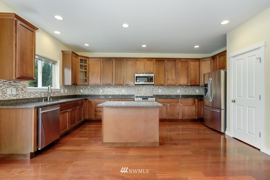 3705 224th Street Southeast Bothell, WA 98021 - Photo 14 of 35 a large kitchen with stainless steel appliances granite countertop a stove a sink dishwasher and a refrigerator with wooden floor