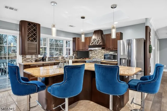 a kitchen with stainless steel appliances granite countertop a refrigerator a sink dishwasher a dining table and chairs with wooden floor