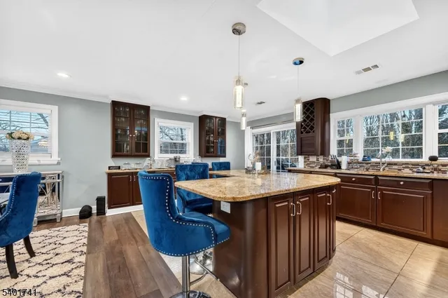 a dining hall with stainless steel appliances granite countertop a sink a stove a dining table and chairs with wooden floor