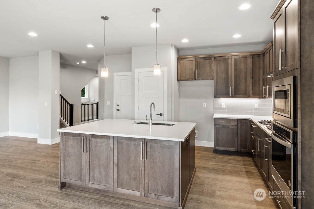 21423 Royal Anne Road, Unit RM1 Bothell, WA 98021 - Photo 25 of 26 a large kitchen with stainless steel appliances kitchen island granite countertop a sink a stove and a refrigerator